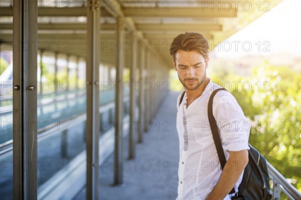 Handsome fit man in white shirt outdoor in city setting, looking away