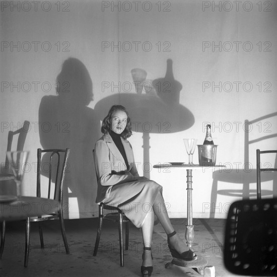 Shadow in photography. A young unknown actress during the filming of Ingmar Bergmans movie Secrets of women that had premiere on november 3 1952. The effect of the low position of the lights casts shadows corresponding to the silhuette of the girl, the table and whats on it. Sweden 1950s. Photo Kristoffersson ref BF56-7