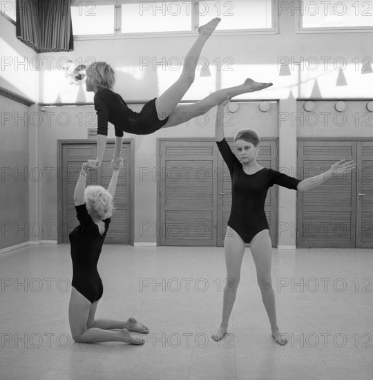 Gymnastics in the 1960s. Three teenage girls are practising gymnastics together in a gymnasium hall. Sweden 1962