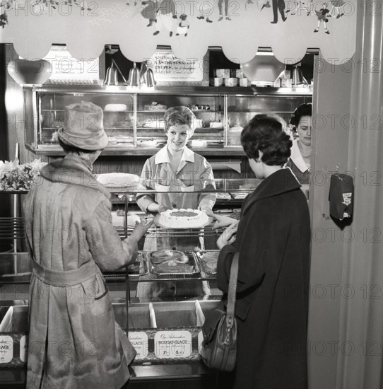 1960s coffee shop. Two women are standing in front of the counter that is full with freshly baked cakes and pastries. Sweden 1960s ref CX80-4