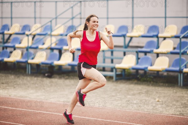 Female runner jogging on stadium track, woman athlete running and working out outdoors, sport and fitness concept. Young woman in sportswear training on a stadium. Sport lifestyle topic