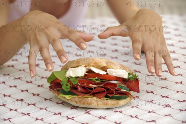 Hungry girl hands over appetising big sandwich with ham and cheese