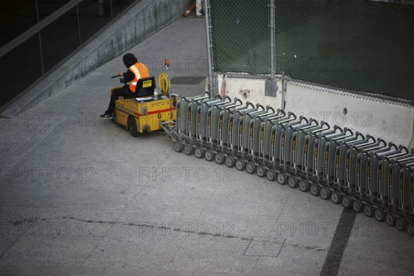 Los Angeles, United States - December 28, 2015: An airport employee at LAX airport pulls a vehicle and luggage cart up a ramp on 28 December 2015 in Los Angeles