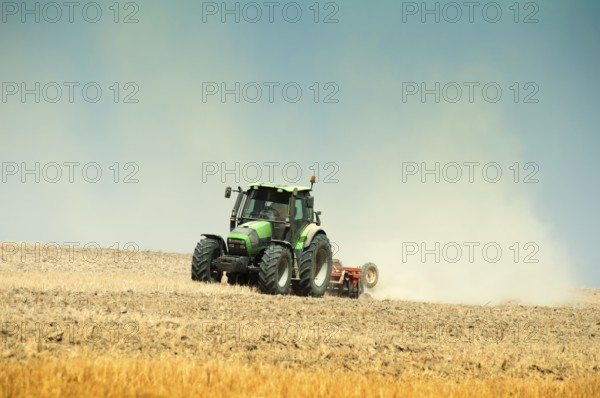 Tractor plowing field on blue sky background