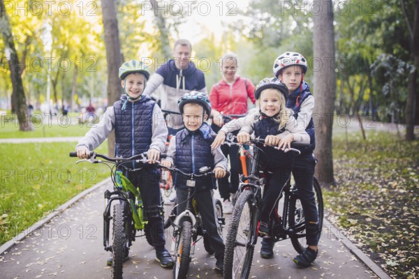 Theme family sports holiday in park in nature. big friendly Caucasian family of six people mountain bike riding in forest. Children brothers and sister stand on the background of parents in a row