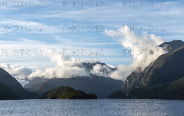 Sun rising over Doubtful Sound, Clouds hanging low on the mountains, South Island of New Zealand