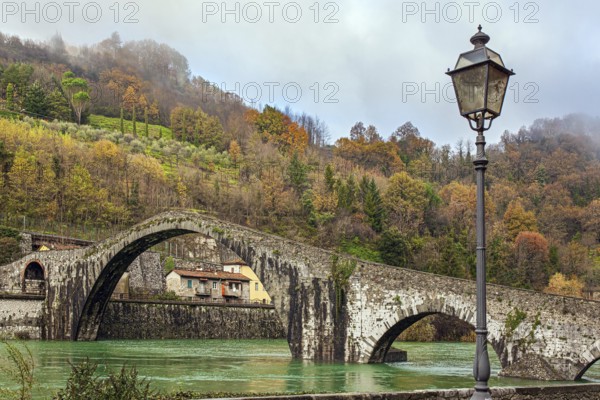 Picturesque stone Devil's Bridge over the Serchio River. Medieval bridge of magnificent architecture built a thousand years ago. Cold windy winter day. Travel to fabulous Italy. Province of Tuscany