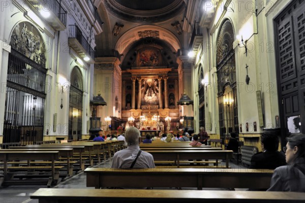 Madrid, Spain, Europe, Interior of a church with pews and an illuminated altar in the background, Europe