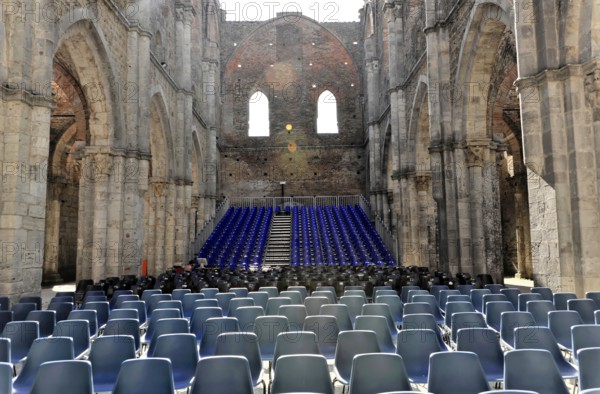 Church ruins of the Cistercian Abbey of San Galgano, Abbazia San Galgano, Gothic, Chiusdino, Tuscany, Italy, Europe, Interior view of a church ruin with many rows of chairs and light-flooded stone walls, Europe