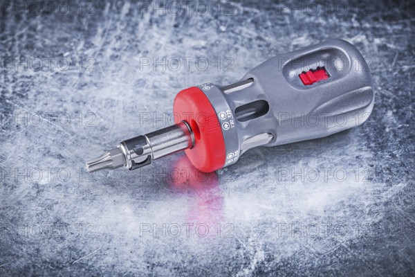 Reversible screwdriver on metallic background construction concept