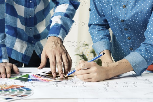 Designers selecting color palette for design project. Human hands, technical drawing and color swatches on desk. Interior design, decoration and renovation. Brainstorming, teamwork and creativity