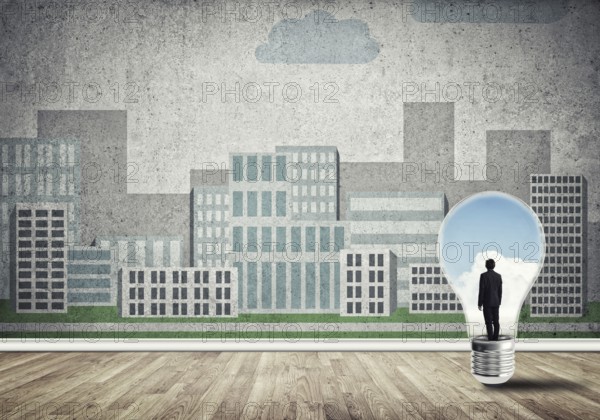 Businessman inside light bulb against city drawn concept
