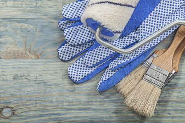Set of paint roller brushes protective gloves on wood board construction concept