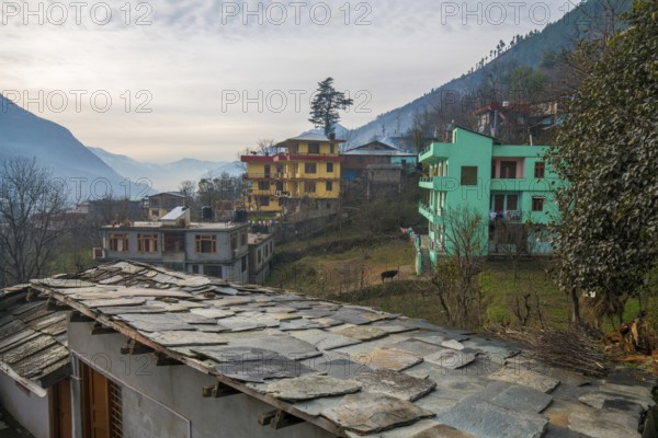 A roof made of thin stone plates nailed to a wooden beam and town Kullu. Foggy morning in Himachal Pradesh at winter