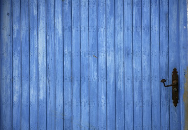 Blue old mediterranean wooden door detail with black handle