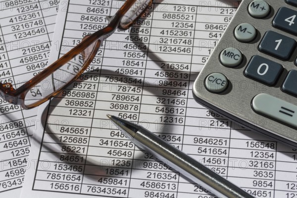 A calculator lies on the figures of a balance sheet and statistics. Symbol photo for turnover, profit and costs. Austria