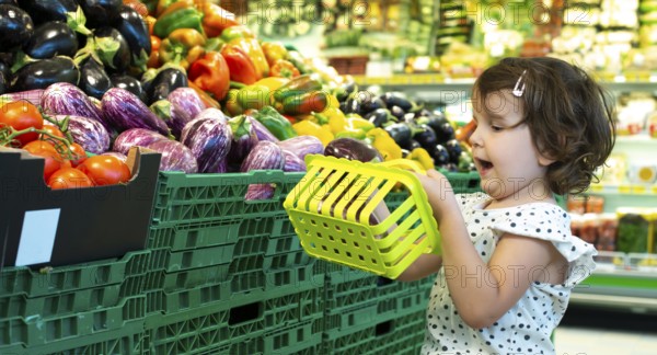 Child shopping eggplants in supermarket. Concept for buying fruits and vegetables in hypermarket. Little girl hold shopping basket