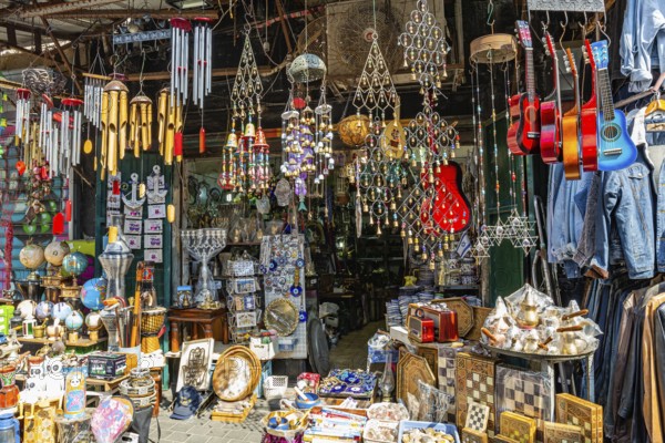The famous flea market in Jaffa. Israel. Garden decorations with jingle bells. Bright multi-colored souvenir guitars. Hanukkah candlesticks, chessboards, finjans and cezves for coffee