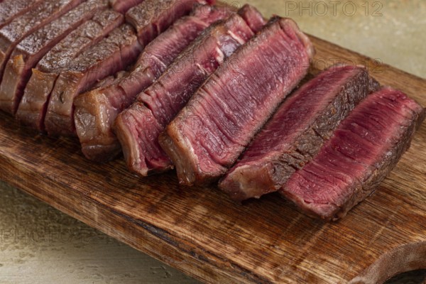 Freshly sliced steak, medium roast, on a wooden cutting board, with a juicy texture and rich color, ready to serve