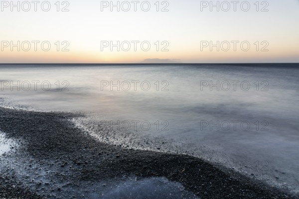 Morning atmosphere, sunrise over the sea, view from the lava beach to the island of Anafi, long exposure, Kamari, island of Santorini, Cyclades, Greece, Europe