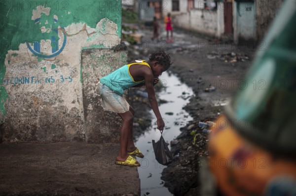 Child throwing rubbish into a gutter on the street, environmental pollution, poverty Kinshasa, Democratic Republic of the Congo, DR Congo