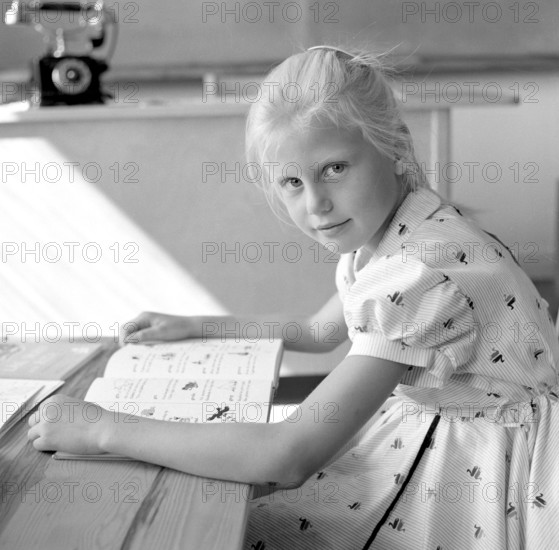 School in the 1950s. A girl is seen sitting at her desk in the classroom reading from the schoolbook in front of her. Sweden 1957 Conard ref 3538