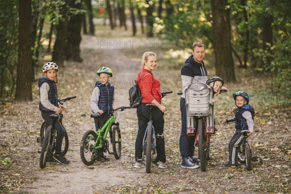 Parents and kids cycling on forest trail. family in warm clothes cycling autumn park. Family mountain bike on forest. active sports outdoor recreation. portrait Family Cycling Through Fall Woodland