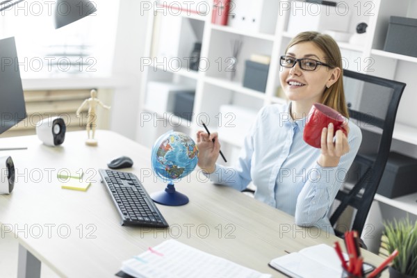 A beautiful red-haired young girl in a white T-shirt and a yellow jacket is working in a bright office. photo with depth of field