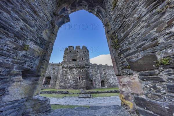 Conwy Castle, view through an arched opening in the castle wall to the tower of the medieval castle with blue sky, Conwy, Wales, Great Britain