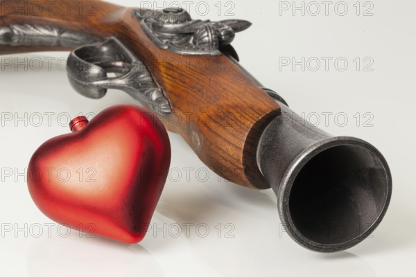 Old gun and red heart on the glass desk
