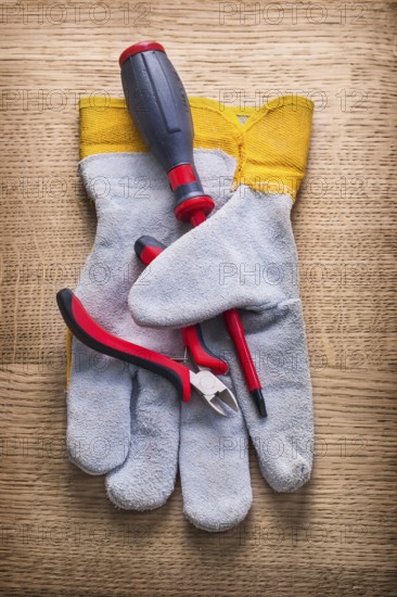 Little nippers screwdriver and protective working glove on wooden board construction concept