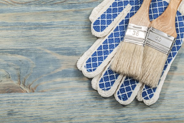 Paint brushes safety gloves on wooden board construction concept