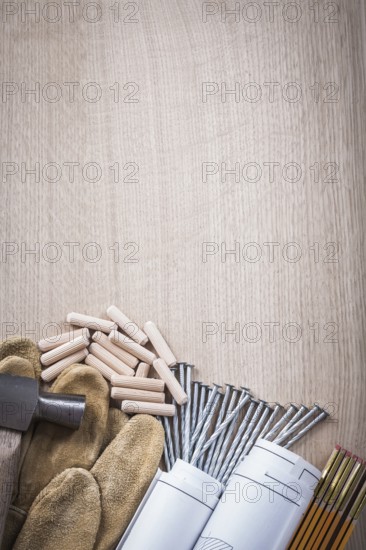 Set of wooden meter dowels construction plans claw hammer leather safety gloves and metal nails on wood board maintenance concept