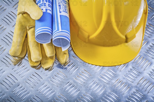 Blue engineering drawings hard hat safety gloves on corrugated metal background construction concept