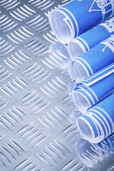 Blue rolled up construction drawings on fluted metal background vertical view
