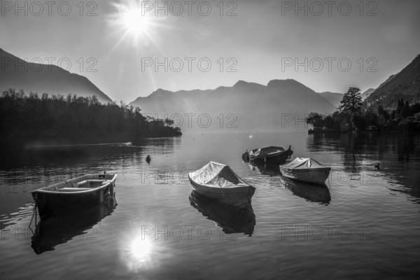 Amazing Lake Como panorama : sunny day in winter, Sheathed boats in water near coast, ducka swimming, Mountains and houses of italian villages and church