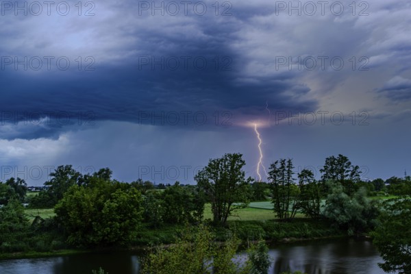 A single bolt of lightning strikes in a dramatic thunderstorm scene with dark clouds, Bogen, Lower Bavaria