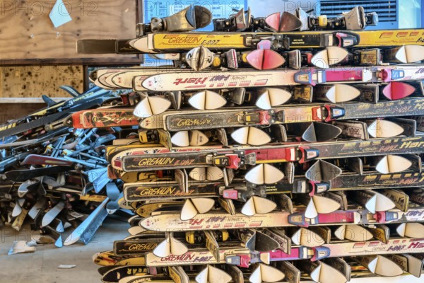Goesan, South Korea. May 29, 2020: Snow skis from various manufactures stacked in rows in sunlit room at abandoned bankrupt ski resort