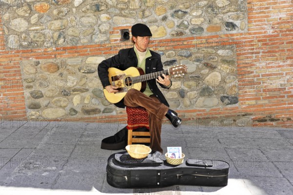 Granada, Andalusia, Spain, Europe, Musician playing guitar on the street next to an old stone wall, Europe