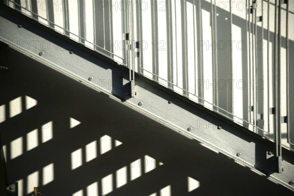 The façade of a residential building with an external staircase that casts a shadow
