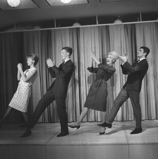 Dancing in the 1960s. The dance Hully Gully is being made popular and here are men and women dancing the new craze. Hully Gully was a type of unstructured line dance and consisted of a series of steps and was relatively simple and easy to execute. Hully Gully can be seen performed by actor John Belushi in the film Blues Brothers. Notice the typical BeeHive hairdo on the blonde girl. Picture taken 1963