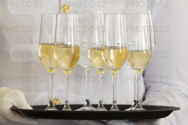Waiter holds a tray of white wine, champagne and water
