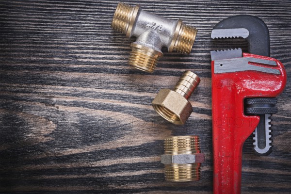 Set of monkey wrench brass equal tee nipple hose connector on wooden board plumbing concept