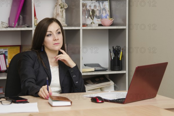Thoughtful girl in the office head table sits at computer and holds hand of person
