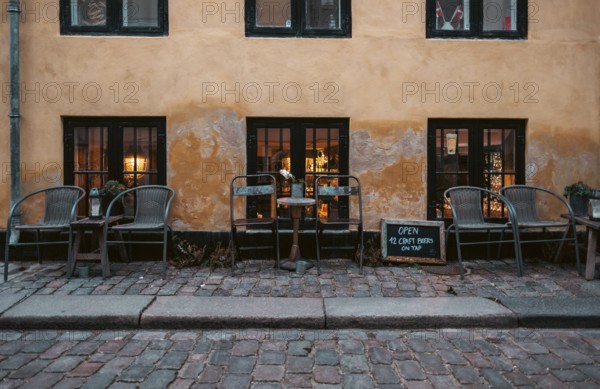 Outdoor cafe seating on cobblestone street with warm lighting and a rustic atmosphere in central Copenhagen, Denmark, Europe