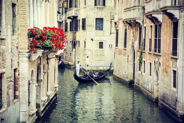 Typical canal in Venice, Italy with traditional gondola in the distance