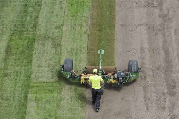 Workers laying grass in a roll on a football field at the stadium in Lubin, Poland, Europe