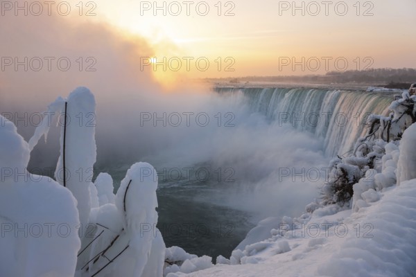A frozen Horseshoe Falls at sunrise with mist and snow creating a calm and serene winter landscape in Niagara Falls, Ontario, Canada, USA, North America