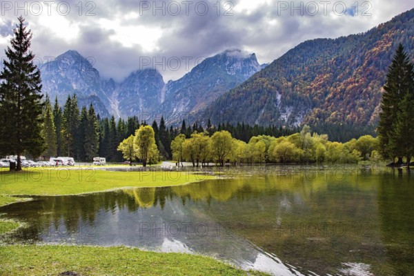 Picturesque lake Fusine in Northern Italy. The smooth surface of the water reflects the surrounding forests and mountains. Mountains covered in morning mist