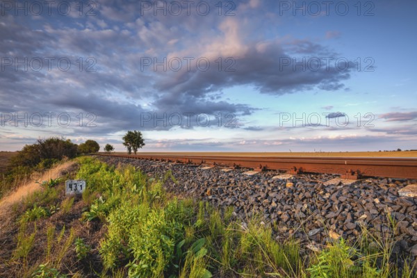 Old Railway tracks running through a field stretch to rural countryside at sunset. Single railway track at sunset, Czech Republic, Europe